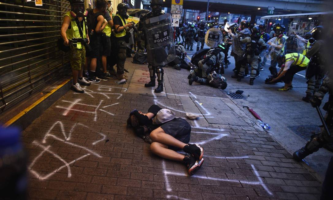 Homem caído no chão cobre o rosto enquanto polícia confronta manifestantes pró-democracia em Hong Kong durante protestos de 2019 Foto: MOHD RASFAN / AFP
