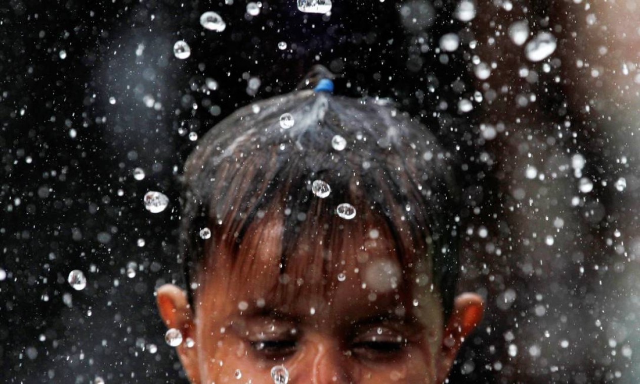 Uma menina migrante com queimaduras de sol na pele é banhada por sua mãe com água da chuva enquanto eles participam de uma caravana rumo à Cidade do México, em Mapastepec, México, 31 de outubro de 2021. REUTERS / Daniel Becerril TPX IMAGENS DO DIA Foto: DANIEL BECERRIL / REUTERS