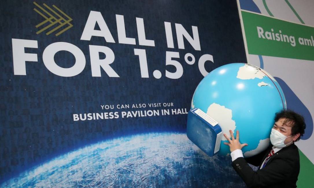 Homem carrega globo durante a COP26, conferência da ONU sobre mudanças climáticas Foto: YVES HERMAN / REUTERS