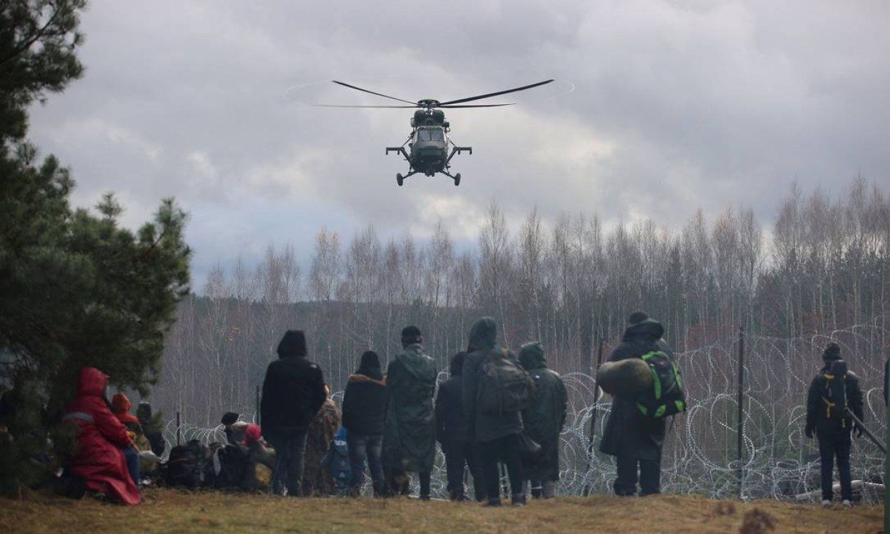 Helicóptero sobrevoa grupo de migrantes perto de uma cerca de arame farpado na tentativa de cruzar a fronteira com a Polônia na região de Grodno, Bielorrússia Foto: BelTA / via REUTERS