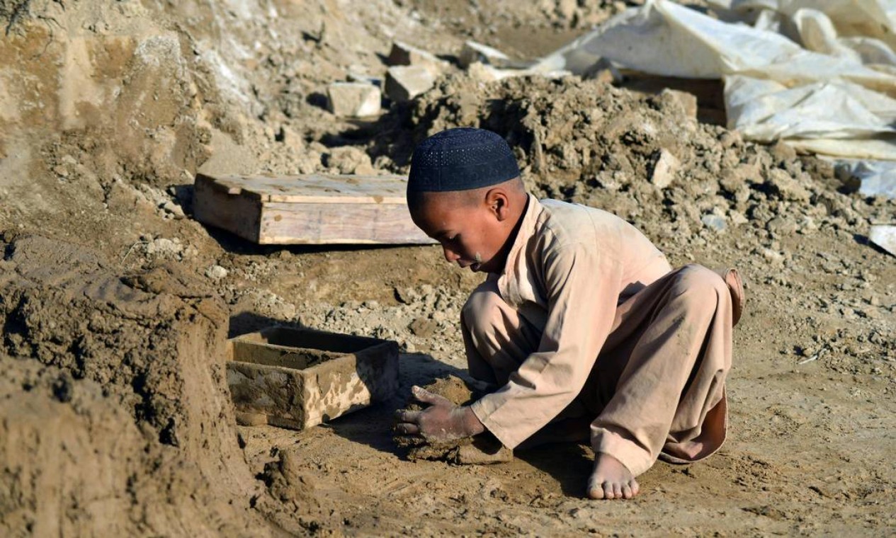 Criança faz tijolos de argila com um molde em um forno de tijolos em Kandahar, Afeganistão Foto: JAVED TANVEER / AFP