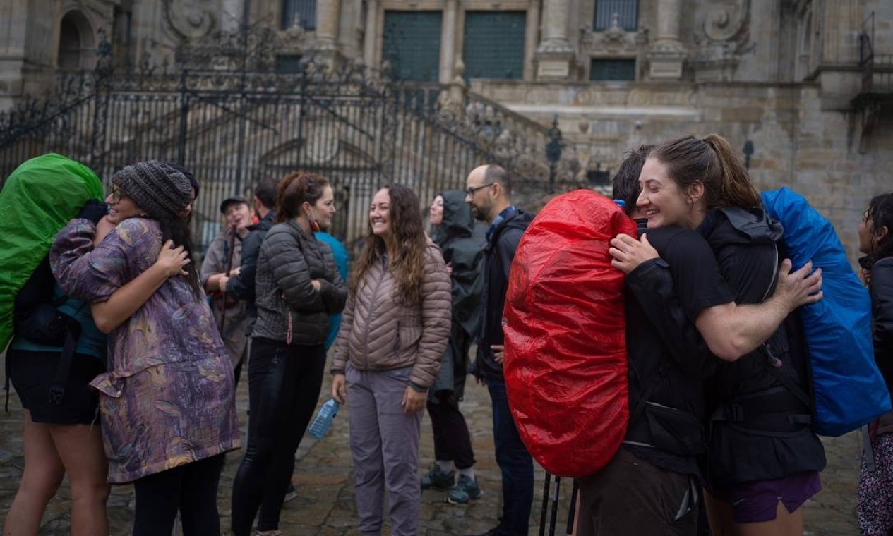 Peregrinos se abraçam em frente à Catedral de Compostela, em Santiago de Compostela, na Espanha, após concluírem o Caminho de Santiago Foto: Samuel Aranda / The New York Times