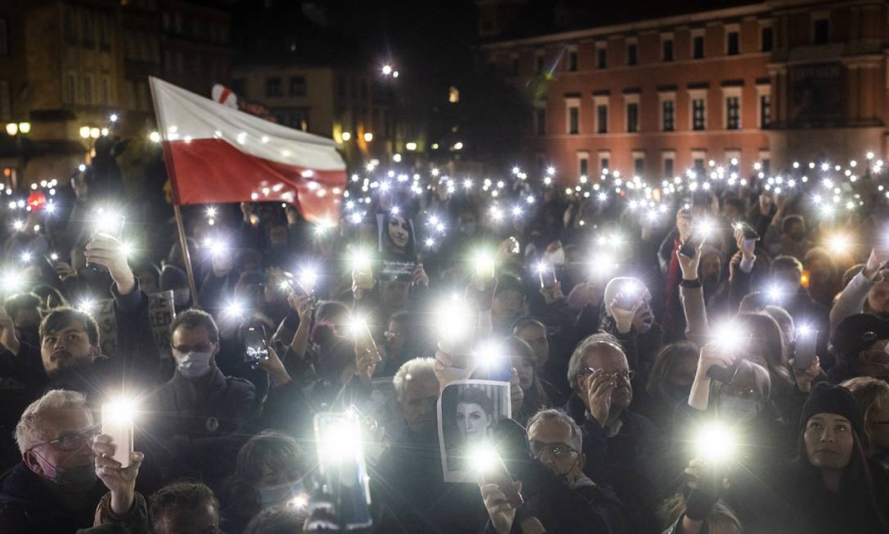 Manifestantes seguram luzes, uma bandeira polonesa e uma fotografia de Iza durante ator em Varsóvia para marcar o um ano da decisão do Tribunal Constitucional que impôs proibição quase total do aborto, e também para lembrar a morte da polonesa grávida Iza Foto: WOJTEK RADWANSKI / AFP