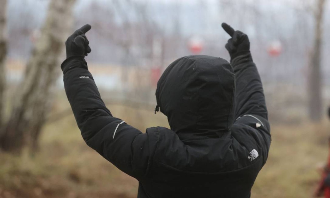 Homem levanta o dedo médio perto de uma cerca na fronteira entre a Bielorrússia e a Polônia em Bruzgi, posto de controle de Kuznica na região de Grodno, Bielorrússia Foto: BelTA / via REUTERS