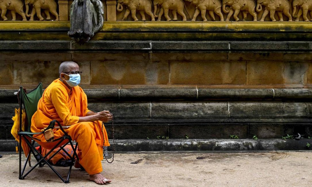Monge budista, usando máscara de proteçao, ora durante Poya, um festival religioso para marcar a lua cheia, no Templo Kelaniya, no subúrbio Kelaniya de Colombo, Sri Lanka Foto: ISHARA S. KODIKARA / AFP