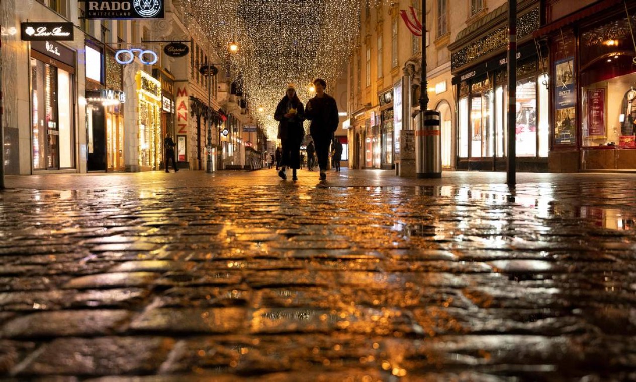 Casal passa por boutiques fechadas na Graben, uma rua no centro da cidade de Viena que normalmente fica lotada de pessoas. A Áustria entrou lockdown para conter a quarta onda de infecções por coronavírus Foto: JOE KLAMAR / AFP