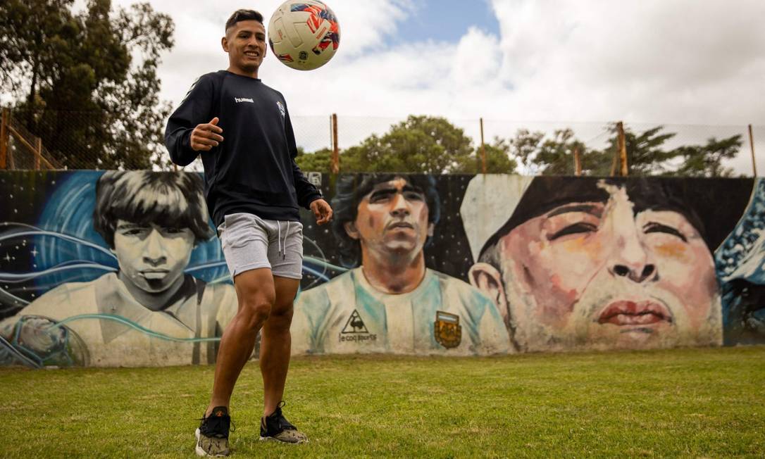 Eric Ramirez, giocatore del Gimnasia y Esgrima de la Plata, lancia la palla davanti a un murale con i ritratti della leggenda del calcio Foto: TOMAS CUESTA / AFP