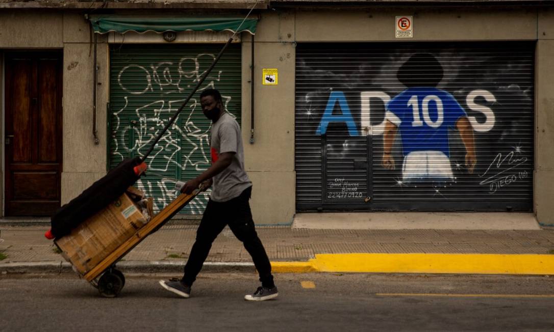 Un uomo spinge una carriola davanti a un murale raffigurante la leggenda del calcio Diego Maradona a La Plata, provincia di Buenos Aires. Foto: TOMAS CUESTA / AFP