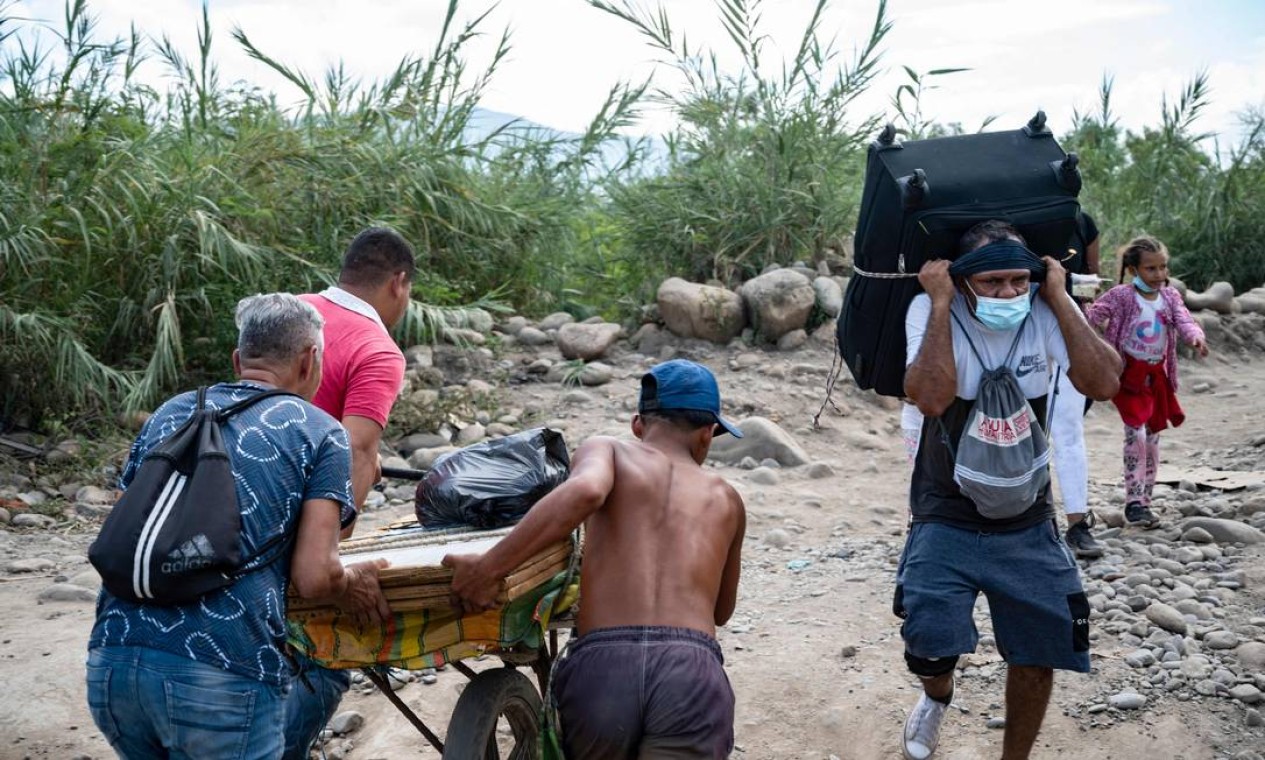 Venezuelanos empurram de volta para casa carreta carregada de compras pelas chamadas "trochas" - trilhas ilegais - em Cúcuta, Colômbia Foto: YURI CORTEZ / AFP
