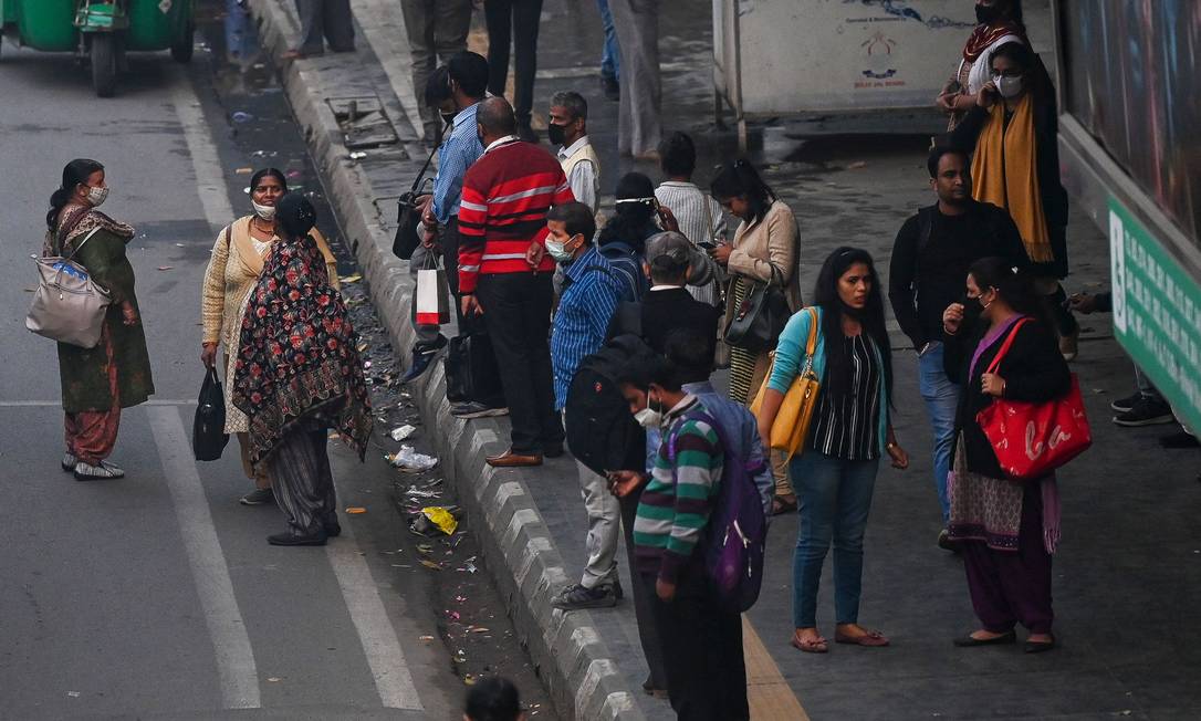Pessoas aguardam ônibus em rua de Nova Délhi Foto: PRAKASH SINGH / AFP