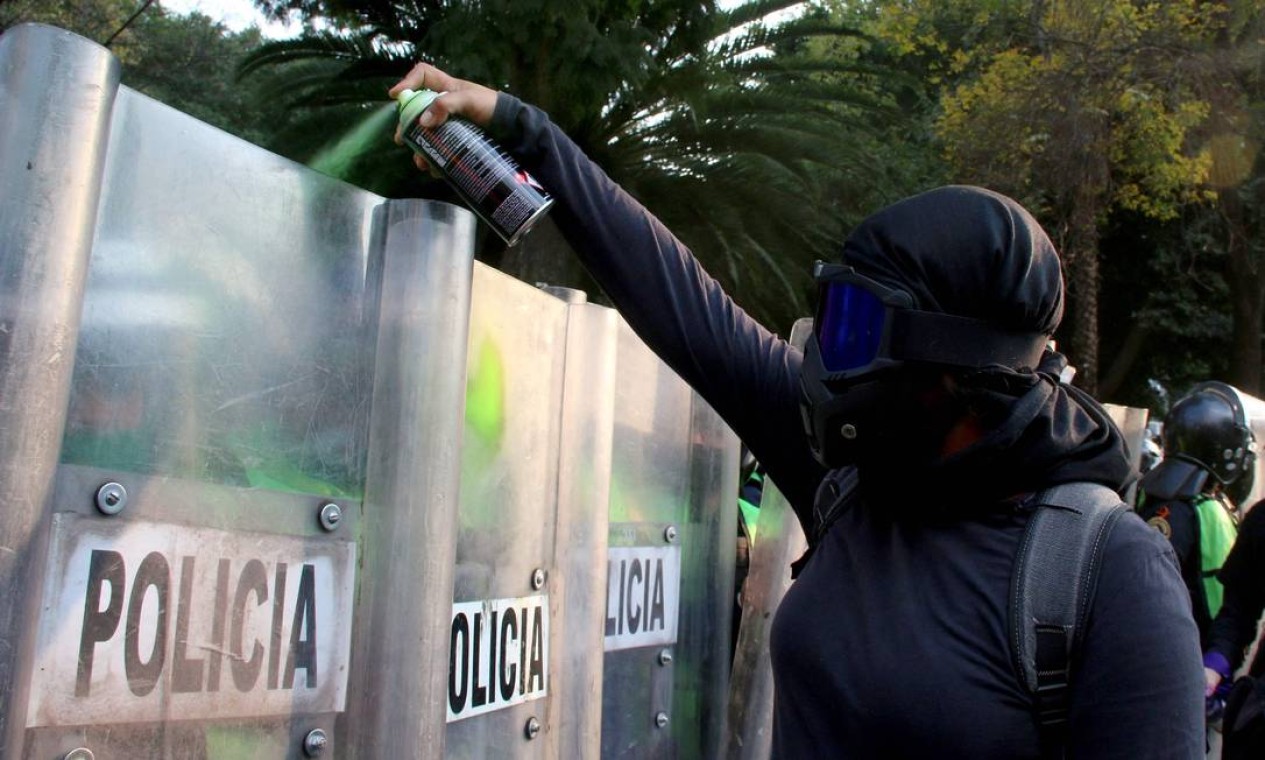 Mulher dispara spray de tinta em policiais de choque durante uma manifestação no Dia Internacional pela Eliminação da Violência contra a Mulher na Cidade do México Foto: SILVANA FLORES / AFP