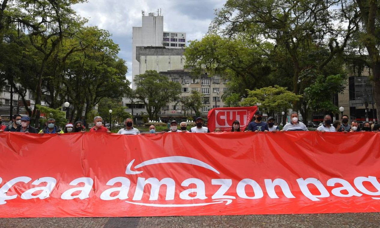 Membros do sindicato de portuários participam de um protesto global do movimento chamado internacionalmente de 'Make Amazon Pay' contra a gigante do comércio eletrônico dos EUA Amazon, no centro de Santos, estado de São Paulo Foto: NELSON ALMEIDA / AFP