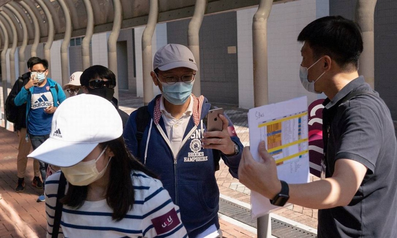 Passageiros escaneam seus dados sanitários no momento do embarque no ônibus 'para lugar nenhum' em Hong Kong, na China Foto: BERTHA WANG / AFP