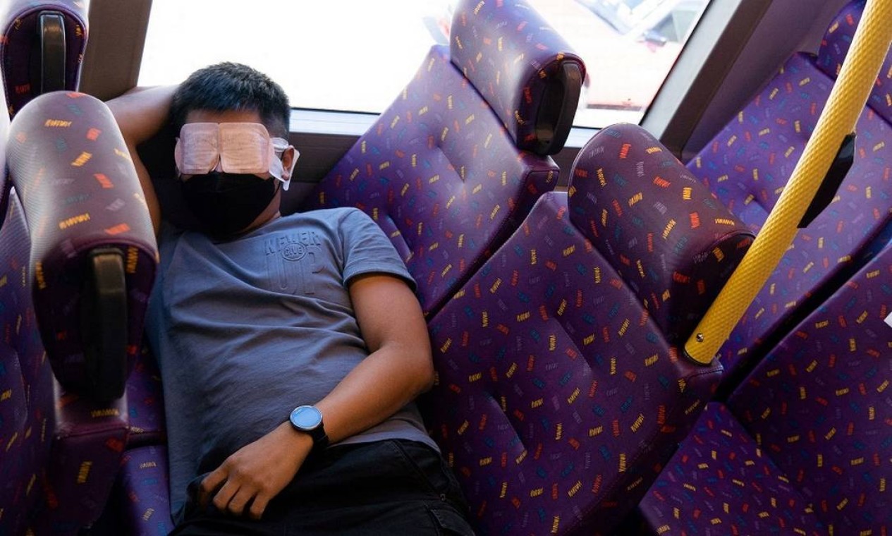 Passageiro aproveita a viagem de ônibus 'para lugar nenhum' em Hong Kong para dormir Foto: BERTHA WANG / AFP