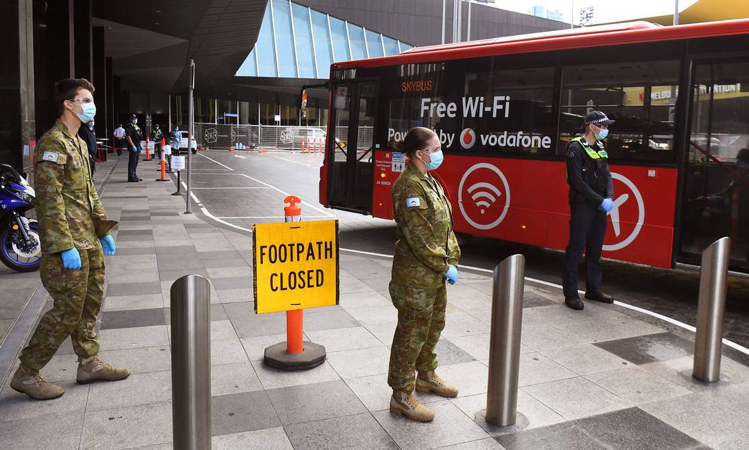 Membros das forças de segurança australianas recebem viajantes para serem encaminhados à quarentena em Melbourne Foto: William West 07-12-2020 / AFP
