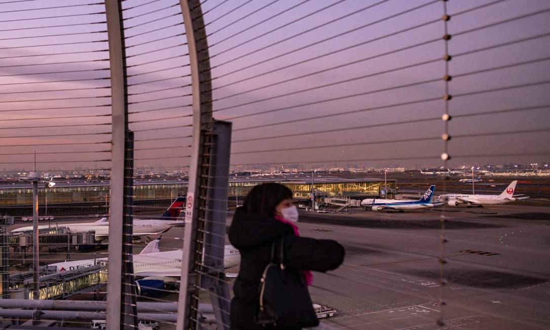 Mulher observa aviões no terminal internacional do aeroporto Haneda, em Tóquio Foto: PHILIP FONG / AFP