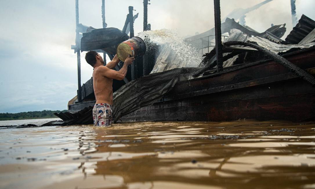 Garimpeiro tenta apagar fogo de uma balsa na beira do rio, na cidade de Borba Foto: Hermes de Paula / Agência O Globo