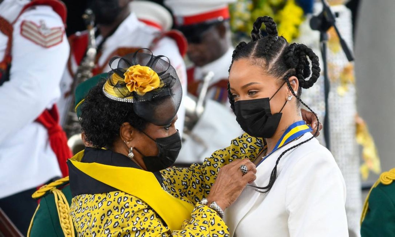 A candora Rihanna Fenty recebe das mãos da presidente da nova República de Barbados, Sandra Mason, medalha de honra que lhe confer titulo de heroina nacional Foto: RANDY BROOKS / AFP