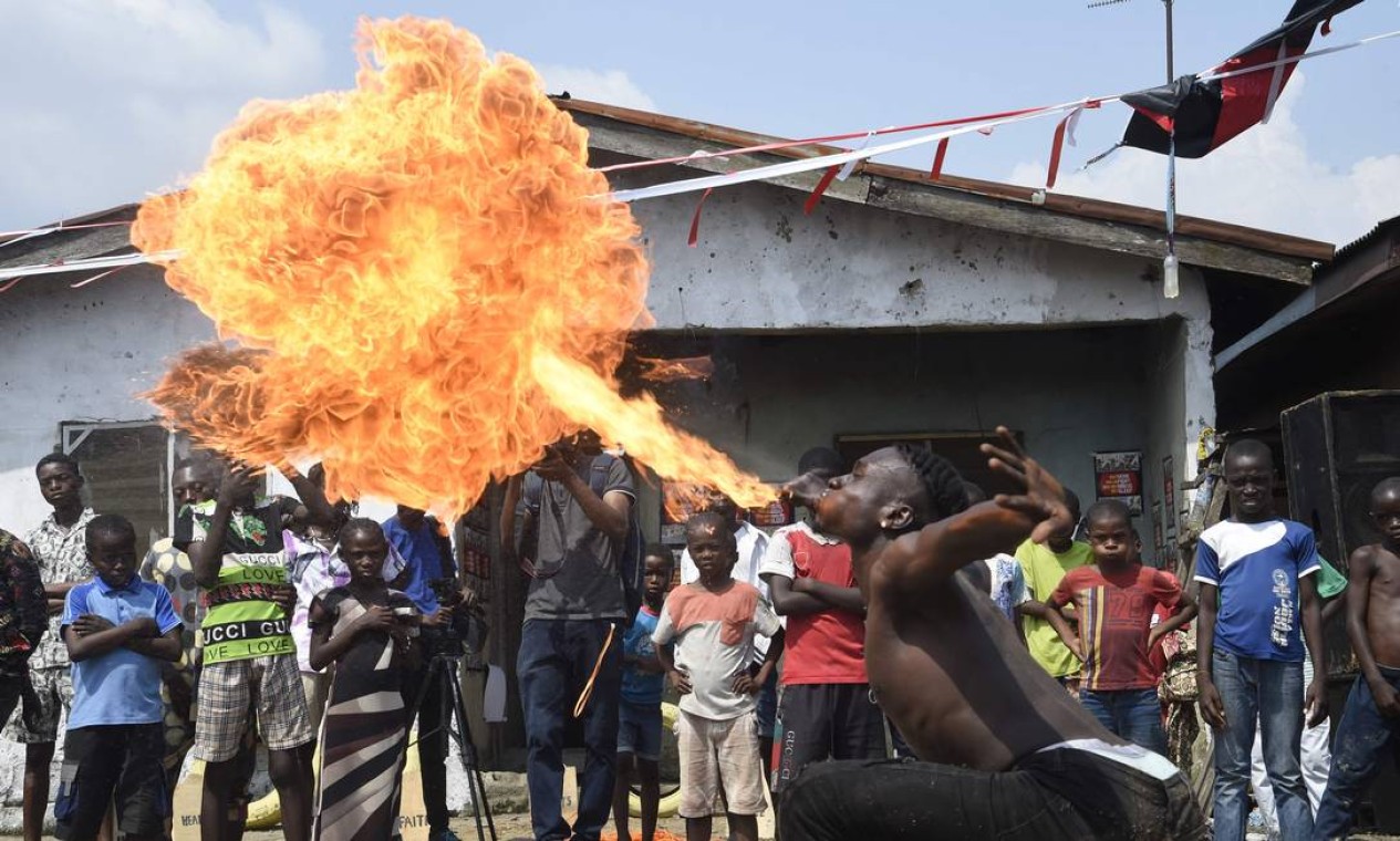 Dançarina cospe fogo durante uma "Festa em uma favela" no distrito de Oworonshoki de Lagos. O projeto cultural visa ressignificar as narrativas que predominam sobre a periferia da capital econômica da Nigéria, limitada aos casos de violência Foto: PIUS UTOMI EKPEI / AFP