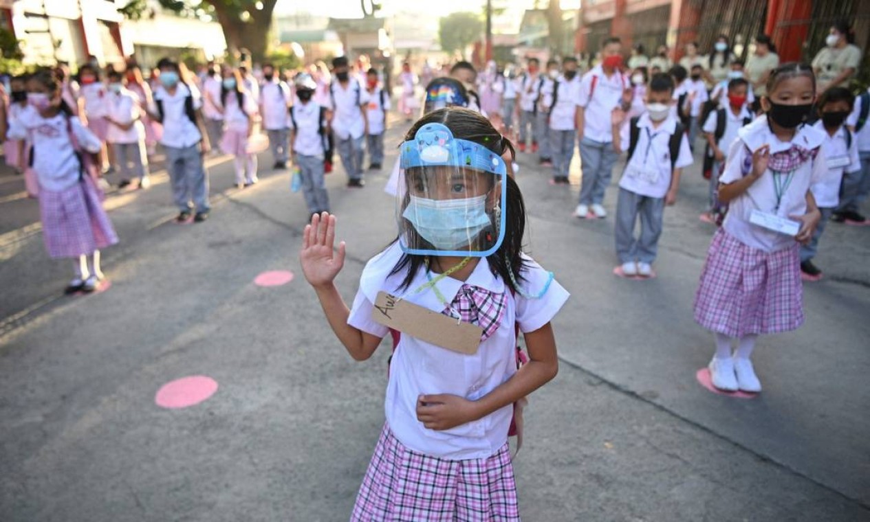 Alunos participam de uma cerimônia de hasteamento da bandeira antes das aulas em uma escola na cidade de Taguig, no subúrbio de Manila, depois que as autoridades afrouxaram as restrições ao coronavírus Foto: TED ALJIBE / AFP