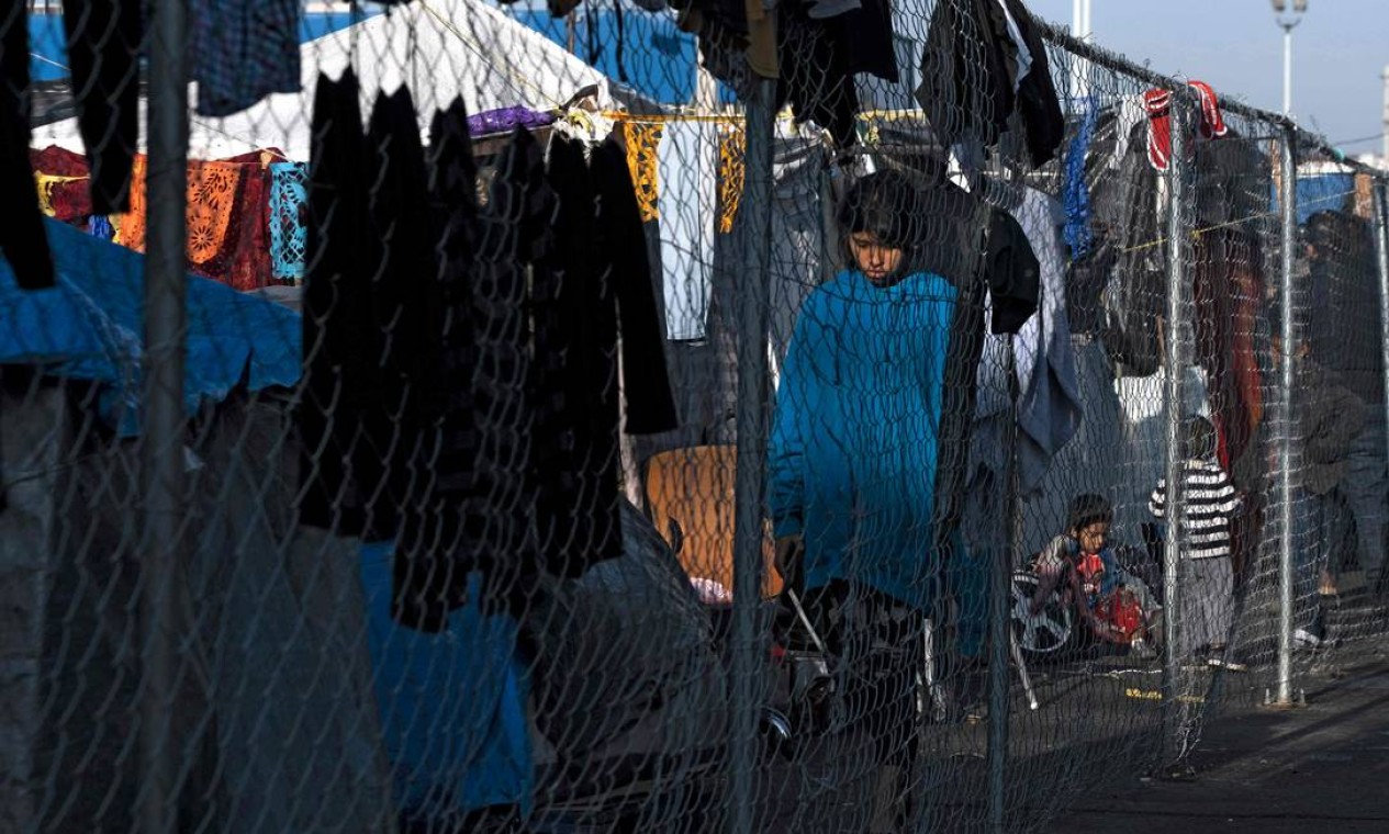 Garota caminha em um acampamento improvisado de requerentes de asilo e refugiados no cruzamento da fronteira de El Chaparral em Tijuana, estado de Baja California, México Foto: GUILLERMO ARIAS / AFP