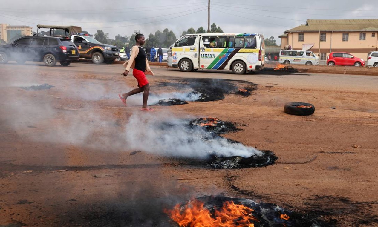 Mulher passa por pneus em chamas durante confrontos que eclodiram depois que um policial queniano matou várias pessoas e a si mesmo em um ataque violento em Nairóbi, Quênia Foto: BAZ RATNER / REUTERS