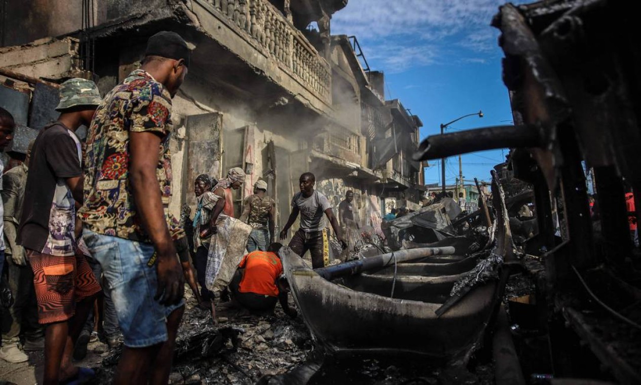 Homens catam pedaços de alumínio no local onde um caminhão-tanque explodiu em Cap-Haitien, Haiti. Pelo menos 62 pessoas morreram com a explosão de um caminhão-tanque Foto: RICHARD PIERRIN / AFP