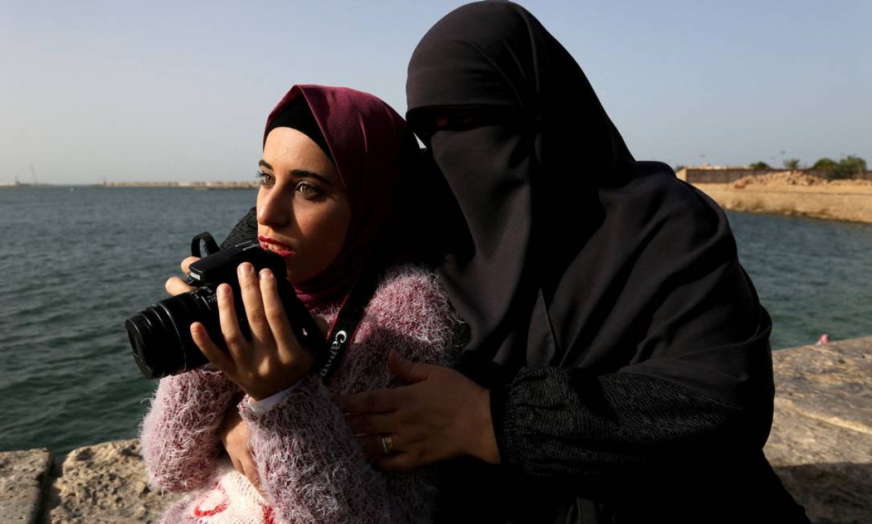 Esaraa Ismail, 22, uma fotógrafa com deficiência visual que depende de seus sentidos de audição e tato para fotografar, é vista com sua mãe em Alexandria, Egito Foto: HANAA HABIB / REUTERS