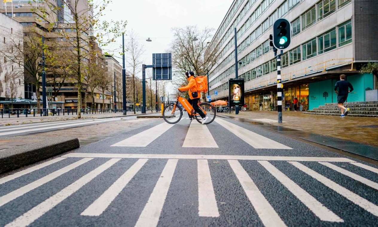 Cciclista que trabalhava para uma empresa de entregas viaja em uma estrada vazia no centro de Rotterdam, no primeiro dia do lockdown da Holanda durante o período de Natal para tentar impedir um surto da variante do coronavírus ômicron Foto: MARCO DE SWART / AFP