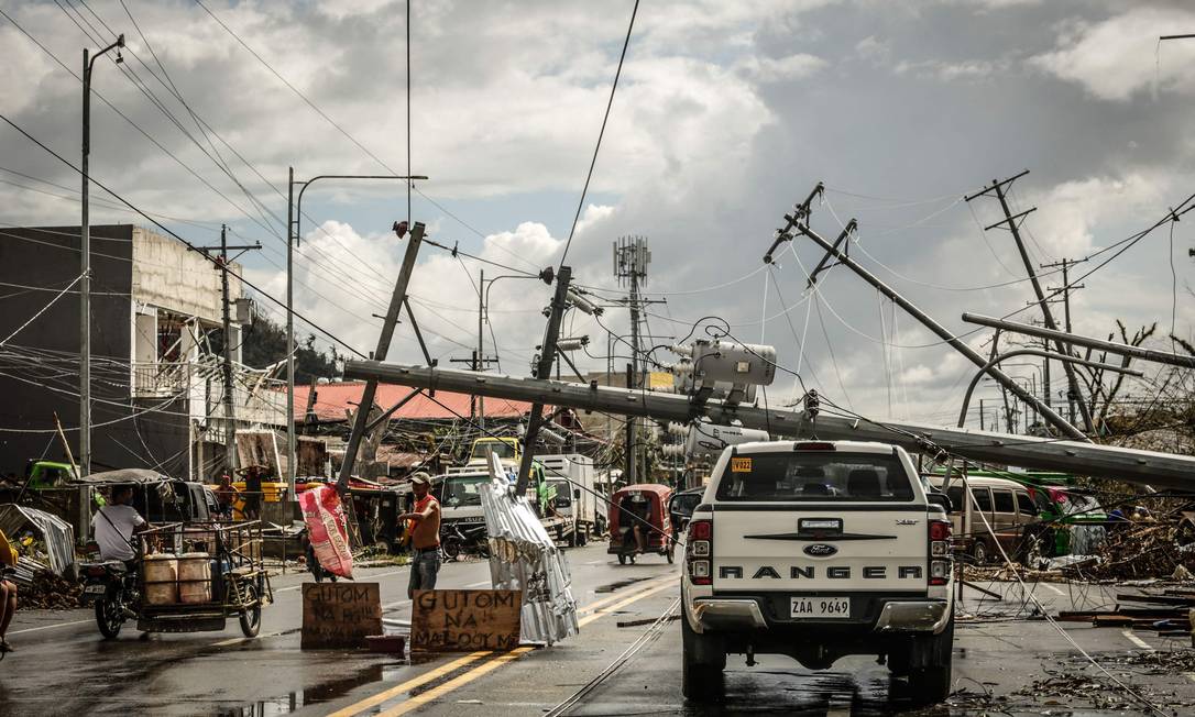 Postes de energia caídos na rua após passagem do tufão Rai pela cidade de Surigao, nas Filipinas Foto: FERDINANDH CABRERA / AFP