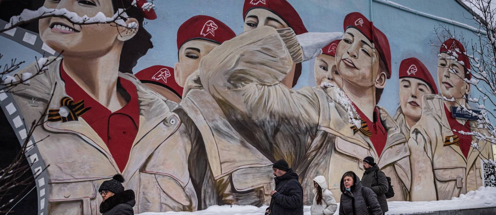 Pessoas passam diante de mural em homenagem à Yunarmiya, o Exército da Juventude, organização ligada ao Ministério da Defesa, em Moscou Foto: SERGEY PONOMAREV / NYT