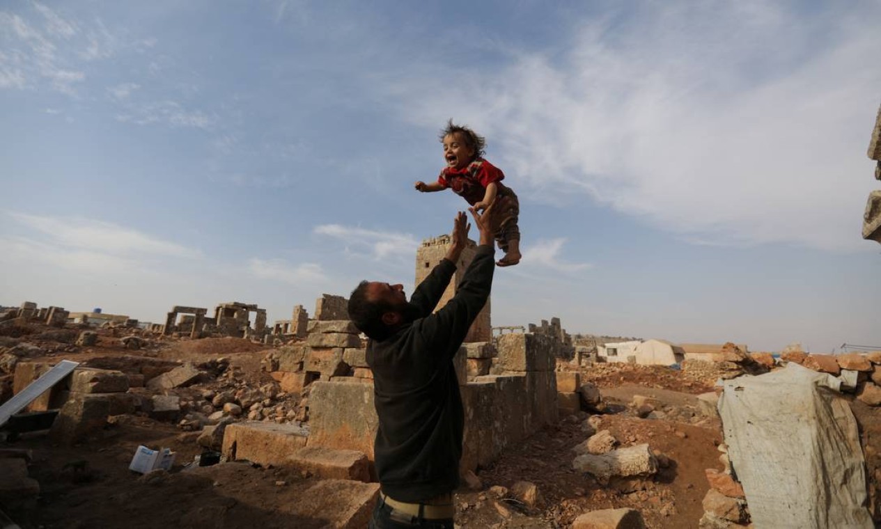 Mohamad Othman, de 30 anos, joga seu filho para o alto no sítio arqueológico de Sarjableh no interior de Idlib, Síria. Sarjableh tornou-se o lar de mais de cinquenta famílias deslocadas do interior de Idlib durante o guerra Foto: KHALIL ASHAWI / REUTERS