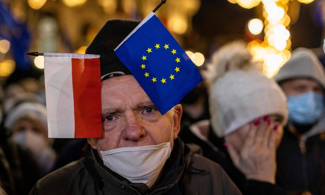 Homem usa chapéu com bandeiras da Polônia e da União Europeia durante protesto contra projeto de lei que críticos afirmam limitar a liberdade de imprensa Foto: WOJTEK RADWANSKI / AFP