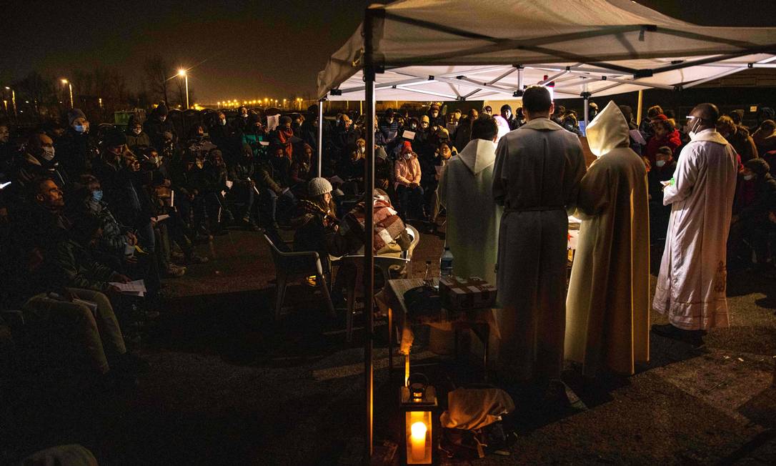Dezenas de migrantes assistem a uma celebração na noite de Natal em Calais, na França Foto: SAMEER AL-DOUMY / AFP/24-12-2021