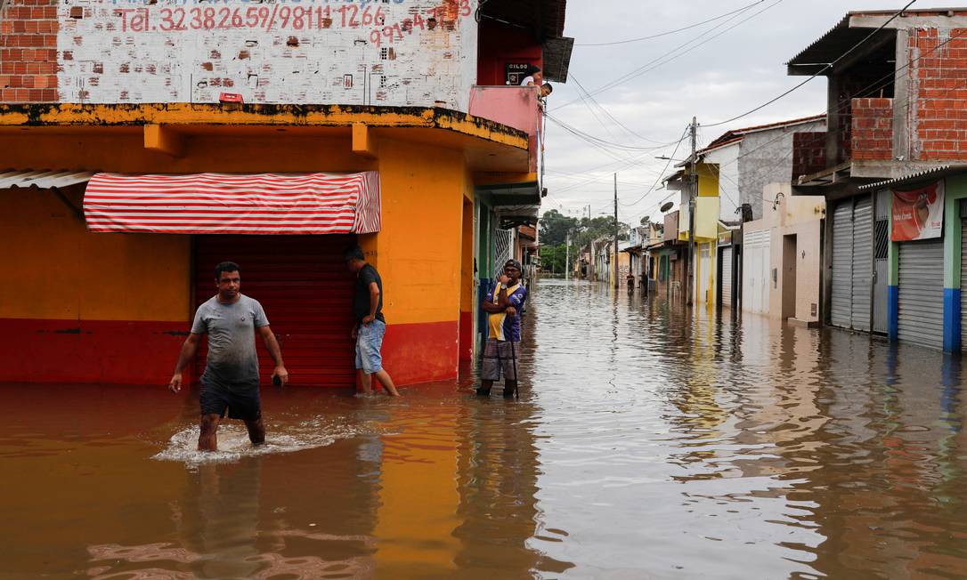 People walk through water along a street during floods caused by heavy rain in Itajuipe, Bahia state, Brazil December 27, 2021. REUTERS/Amanda Perobelli Foto: AMANDA PEROBELLI / REUTERS