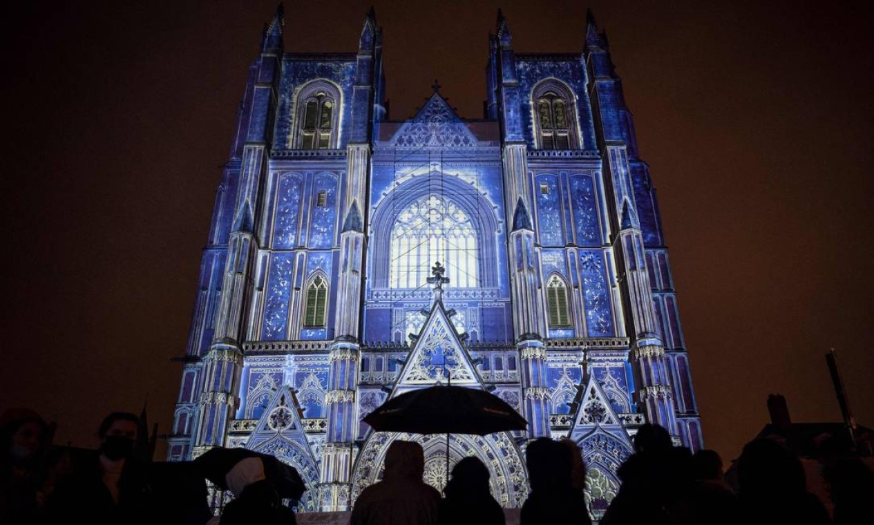 Pessoas observam a Catedral de Saint-Pierre-et-Saint-Paul, na qual estão projetadas imagens inspiradas no pintor francês Alain Thomas, para o espetáculo de luz e som "Lúcia, Mistério da Amazônia", em Nantes, na França Foto: LOIC VENANCE / AFP