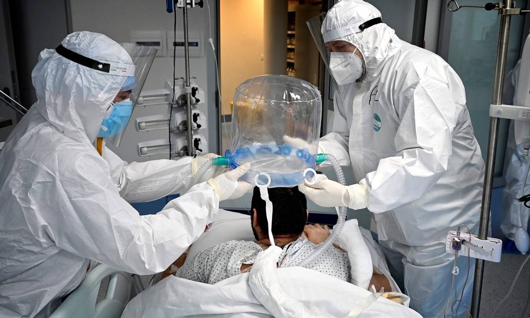 Membros da equipe médica ajudam um paciente a usar uma nova tecnologia não invasiva que pode reduzir a necessidade de intubação na UTI do Instituto de Cardiologia Clínica, em Roma Foto: ALBERTO PIZZOLI / AFP