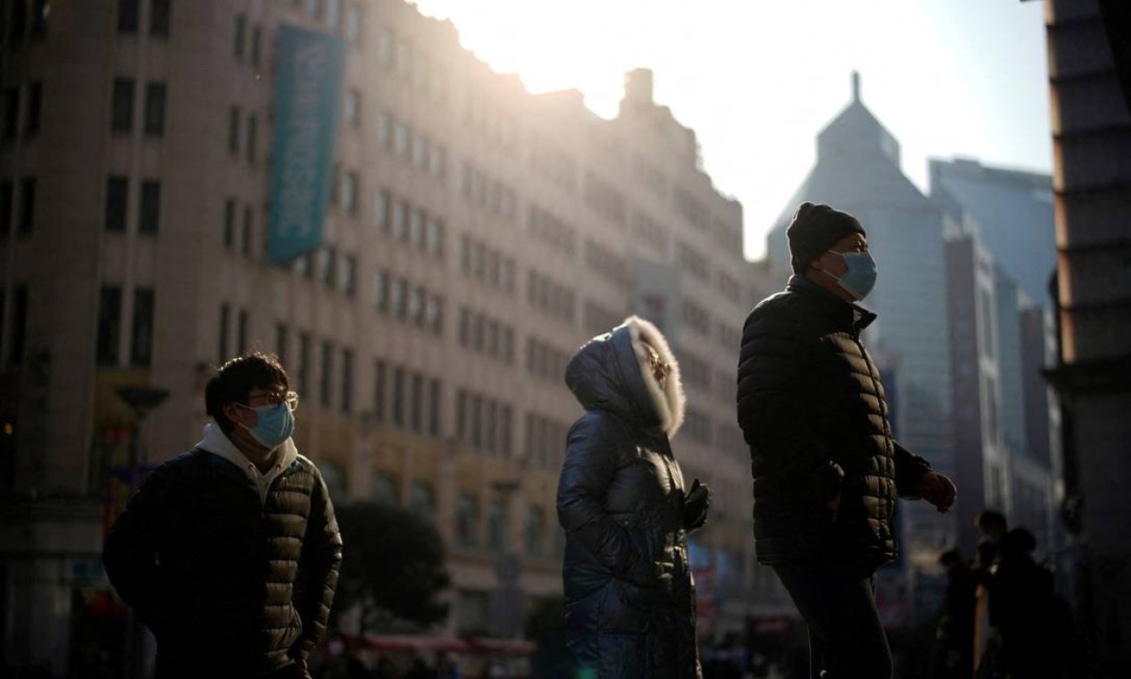 Pessoas com máscaras faciais de proteção caminham na rua, acompanhando novos casos de Covid-19, em Xangai Foto: ALY SONG / REUTERS