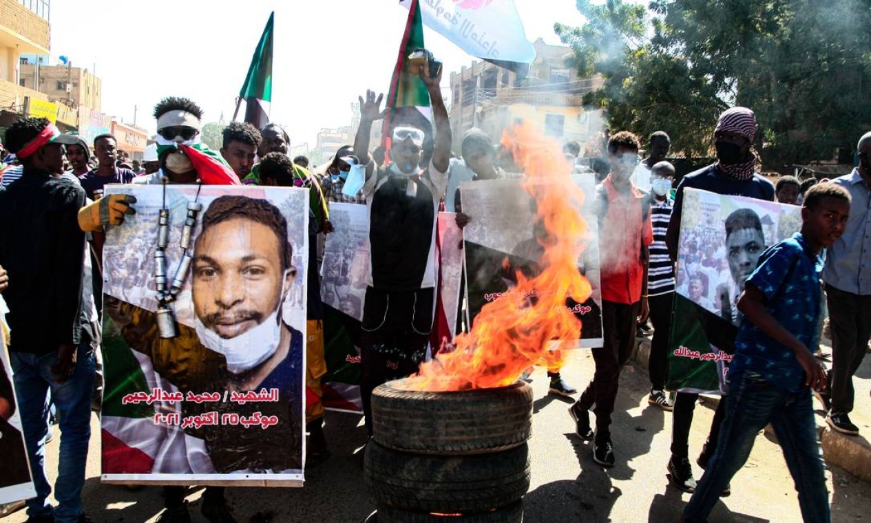 Manifestantes sudaneses carregam cartazes de manifestantes mortos enquanto protestavam na capital, Cartum, contra o golpe do exército, em outubro Foto: - / AFP