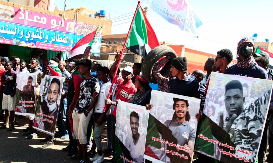 Manifestantes exibem fotos de cidadãos mortos durante protestos contra o governo do Sudão Foto: - / AFP