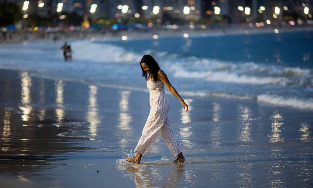 Mulher caminha na orla da praia de Copacabana na véspera do ano novo Foto: DANIEL RAMALHO / AFP