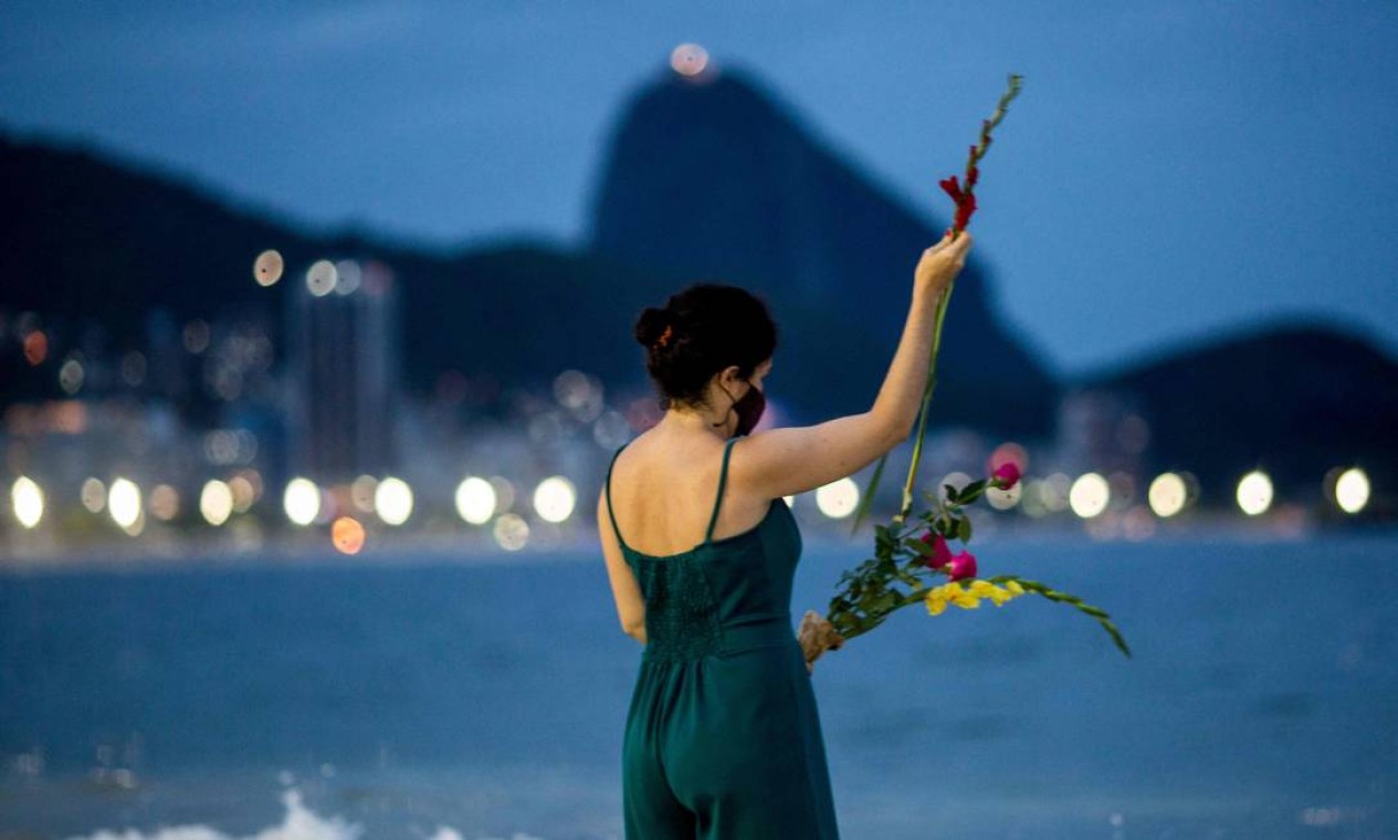 Mulher faz suas preces antes de jogar flores para Iemanjá, deusa do mar, na praia de Copacabana na véspera do ano novo, no Rio de Janeiro Foto: DANIEL RAMALHO / AFP