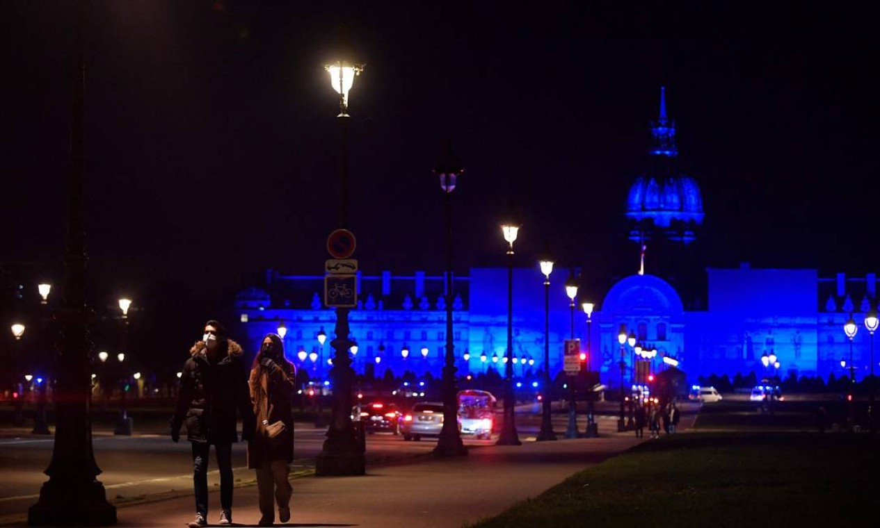 Sasal caminha em frente ao Palácio dos Inválidos iluminado Foto: JULIEN DE ROSA / AFP