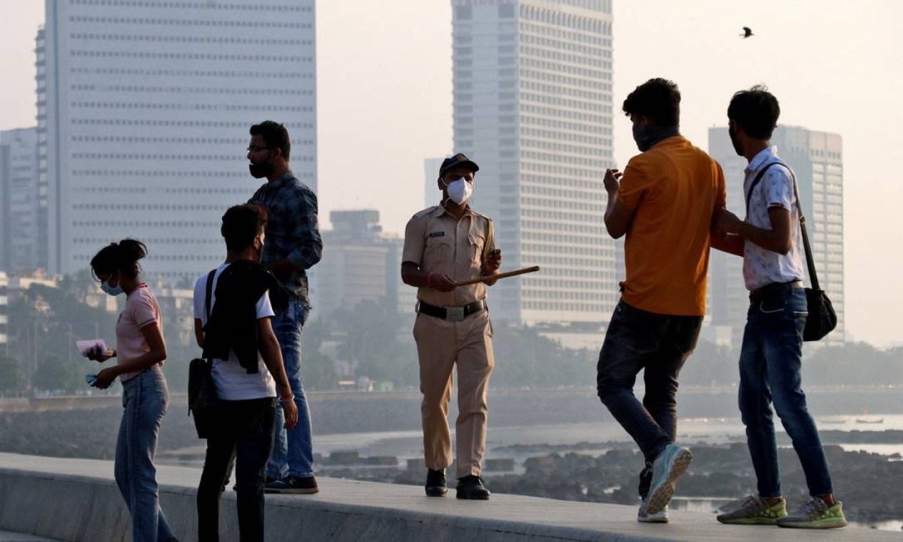 Policial pede às pessoas que saiam do passeio na unidade da Marinha, durante restrições para limitar as reuniões públicas em meio à disseminação do coronavírus em Mumbai Foto: NIHARIKA KULKARNI / REUTERS