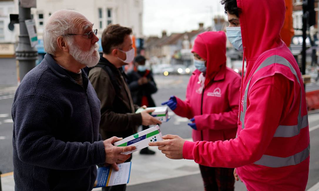 Voluntários distribuem testes rápidos de Covid-19 fornecidos pelo governo, no nordeste de Londres Foto: TOLGA AKMEN / AFP