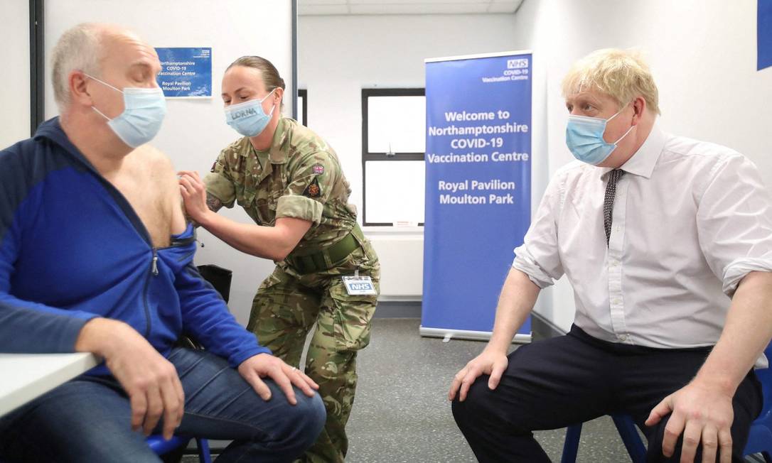 Premier do Reino Unido, Boris Johnson, observa enquanto homem é vacinado contra a Covid Foto: PETER CZIBORRA / AFP