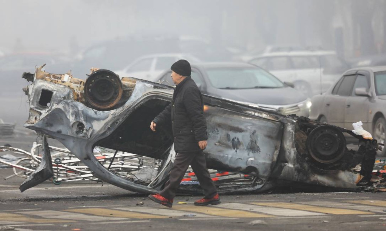 Homem passa por carro incendiado durante os protestos desencadeados pelo aumento do preço do combustível em Almaty, Cazaquistão Foto: PAVEL MIKHEYEV / REUTERS - 06/01/2022