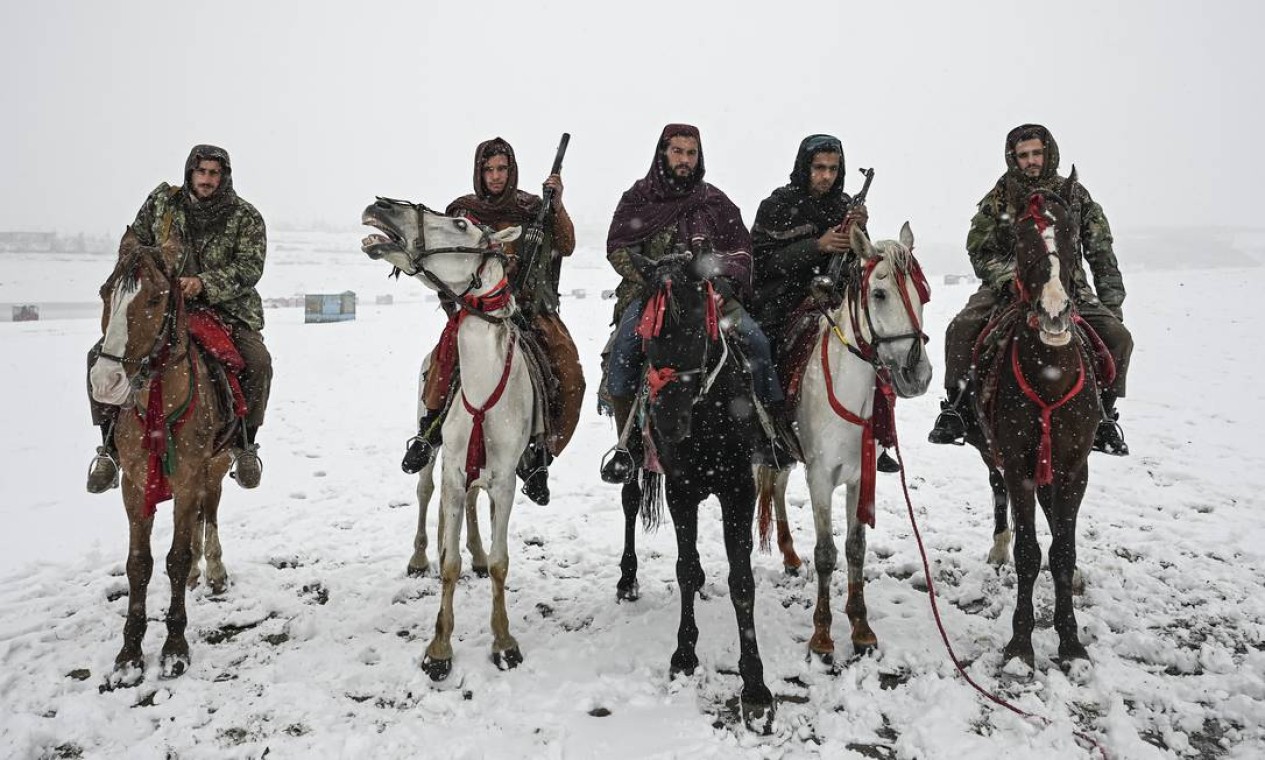 Combatentes do Talibã posam enquanto montam cavalos alugados durante uma nevada no lago Qargha, em Cabul Foto: MOHD RASFAN / AFP