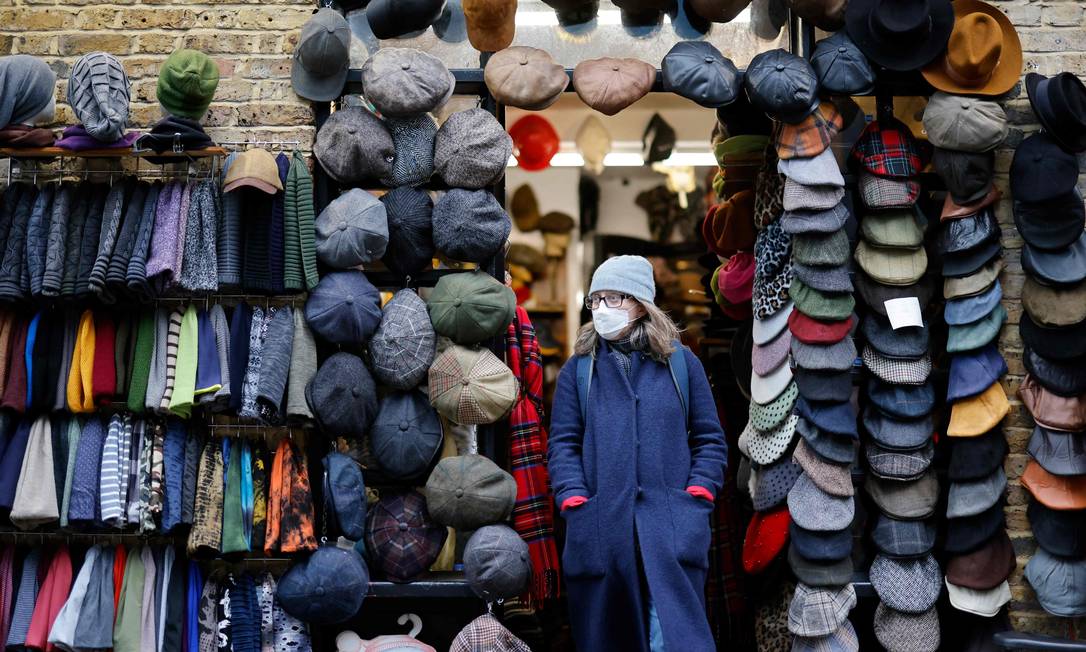 Cliente deixa uma loja no Camden Market, em Londres. Empresas e consumidores do Reino Unido enfrentam novas restrições impostas devido à disseminação da variante Ômicron Foto: TOLGA AKMEN / AFP