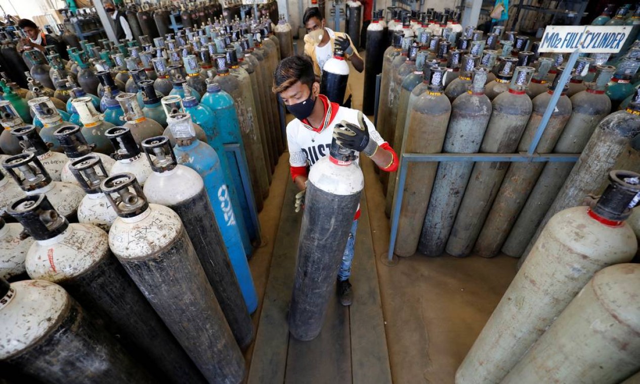 Homens levam cilindros de oxigênio após recarregá-los em uma fábrica, em meio à disseminação da Covid-19 em Ahmedabad, Índia Foto: AMIT DAVE / REUTERS
